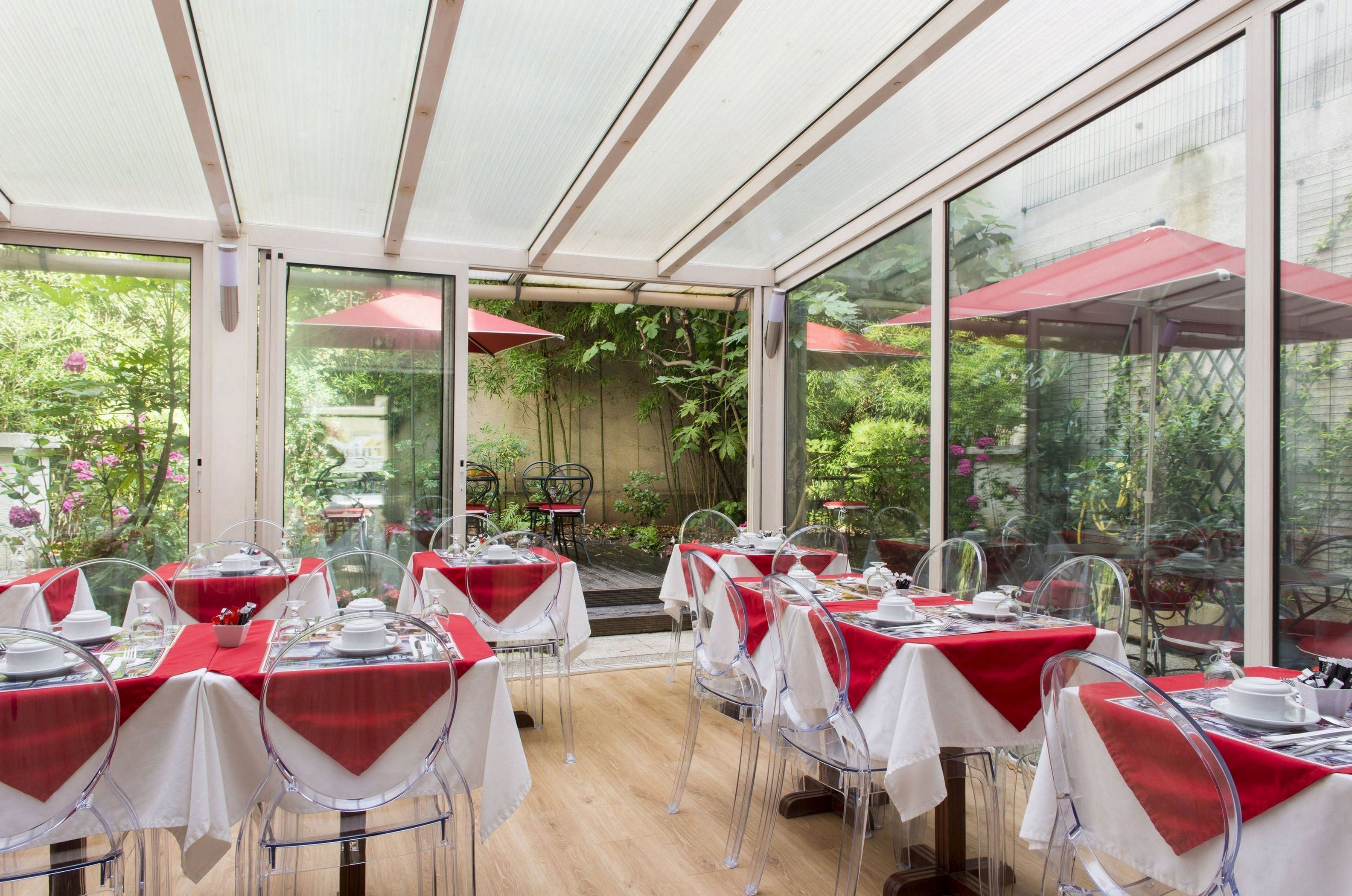 A restaurant with tables set for dining, large windows, and outdoor umbrellas.
