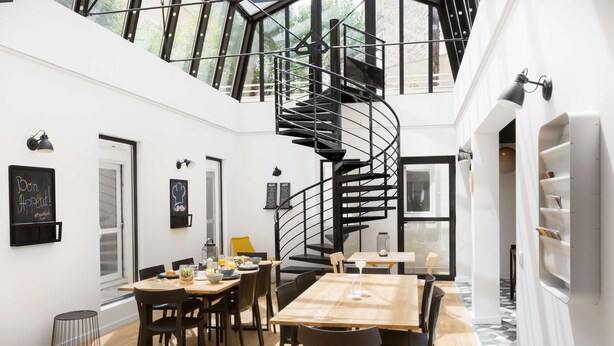 A modern interior with a spiral staircase, dining area, and white walls. - Hôtel Bootcamp (Issy-les-Moulineaux)