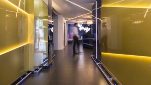 Un corridoio moderno con superfici riflettenti e illuminazione lineare.