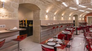 Un ristorante con pareti in pietra, illuminazione moderna e sedie rosse.