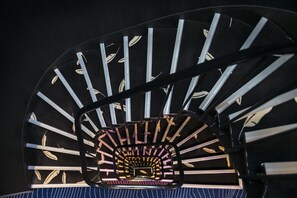 Een wenteltrap met een centraal uitkijkplatform, omringd door metalen leuning en gebeeldhouwde vloertegels.
