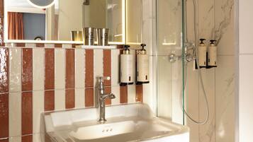 Une salle de bain avec une douche à parois de verre, un lavabo blanc et un miroir doté d’un cadre éclairé.