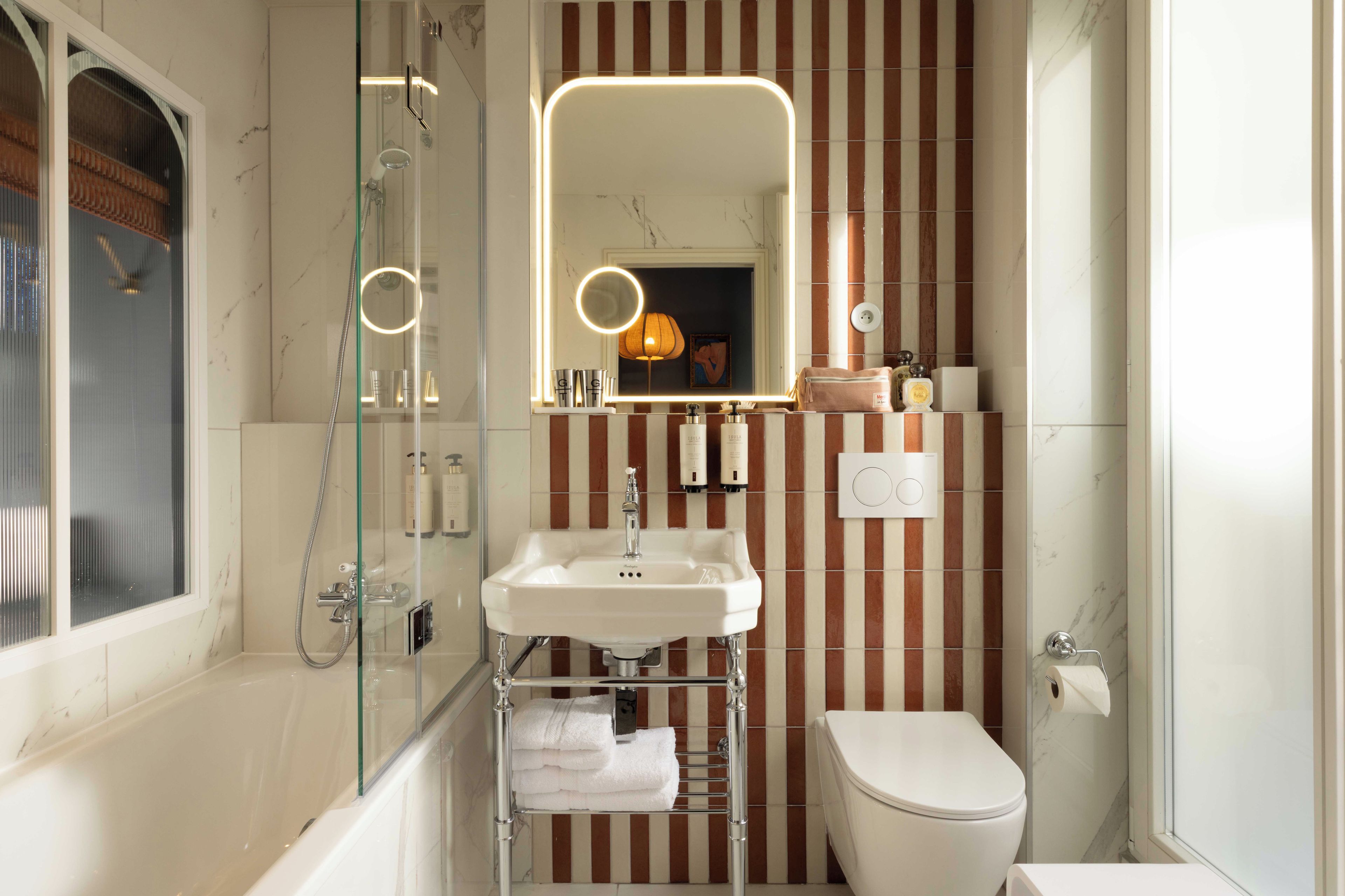 Een badkamer met een douchecabine van glas, een witte wastafel en een toilet.