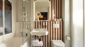 Een badkamer met een douchecabine van glas, een witte wastafel en een toilet.