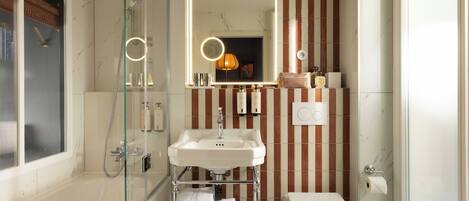 A bathroom with a glass-enclosed shower, a white sink, and a toilet.