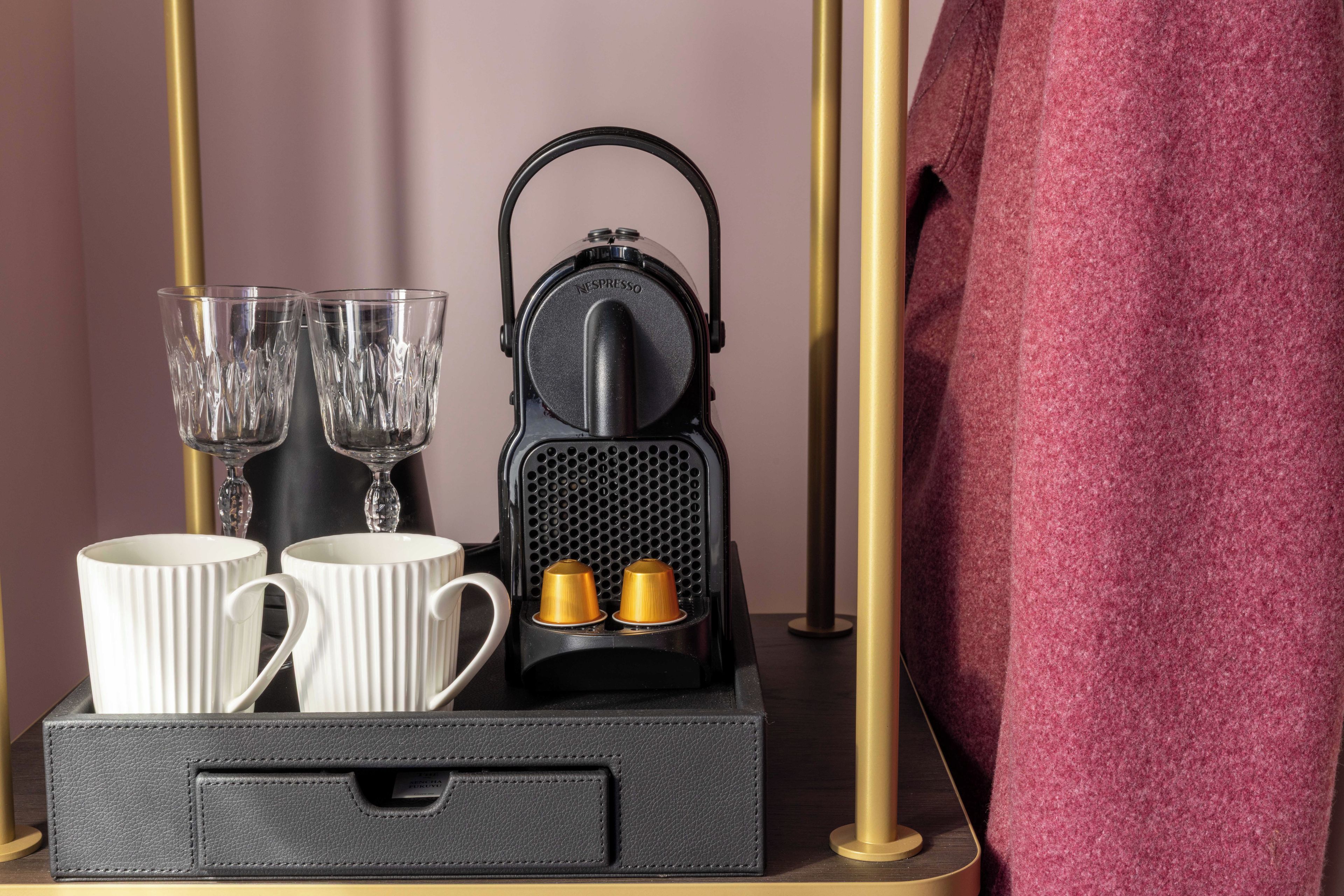 A coffee maker with two cups and two glasses on a tray.