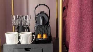 Een koffiezetapparaat met twee kopjes en twee glaasjes op een dienblad.