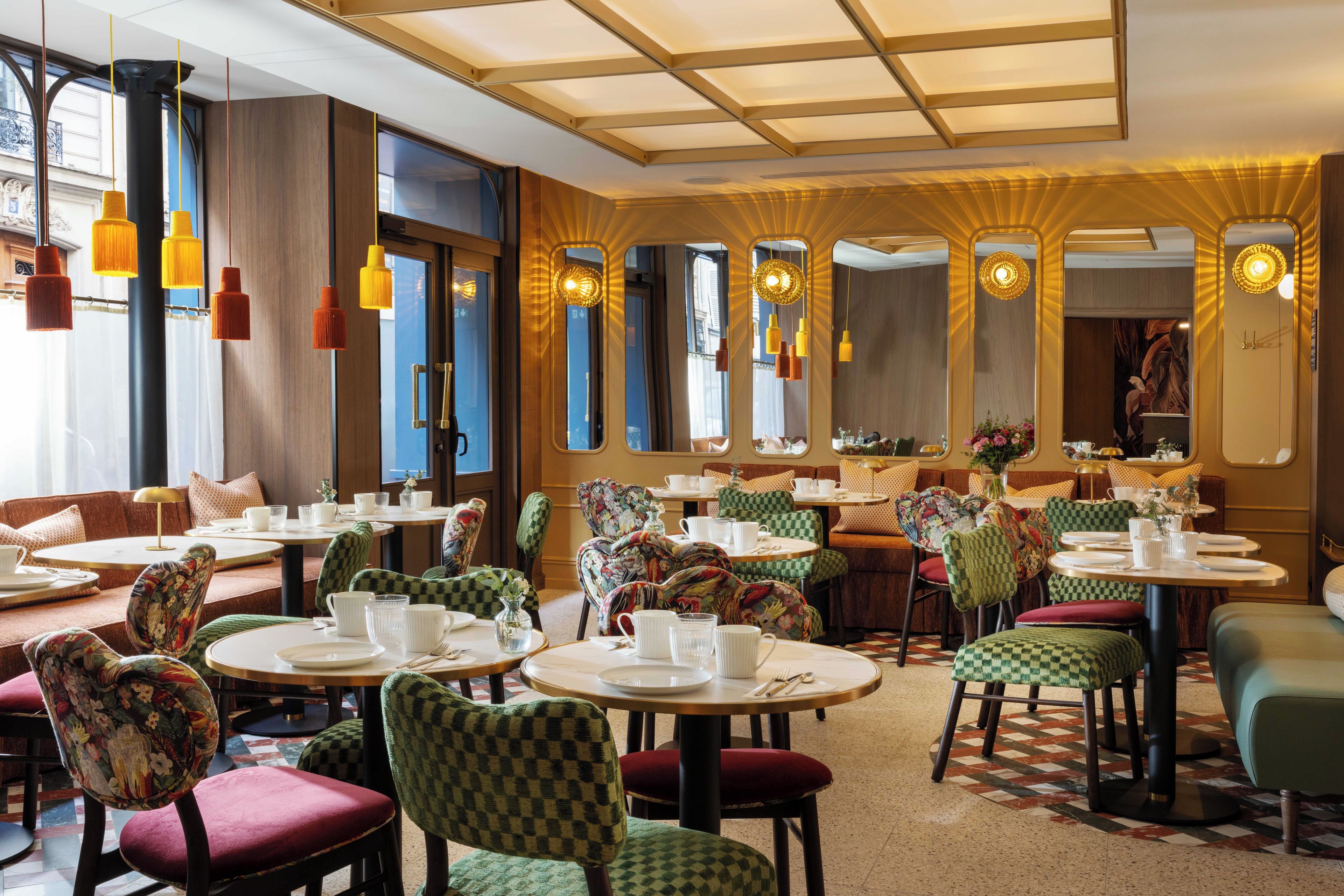A restaurant interior with round tables, checkered chairs, and hanging pendant lights.