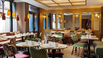 A restaurant interior with round tables, checkered chairs, and hanging pendant lights.