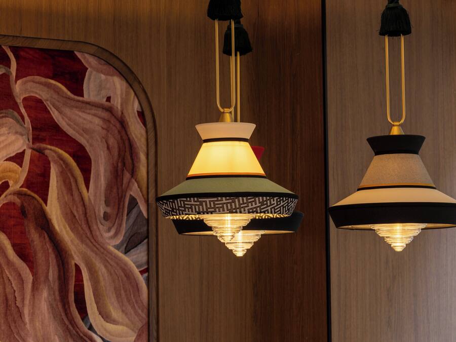 Een kamer met een groot abstract schilderij aan de wand en twee hanglampen met decoratieve lampenkappen.