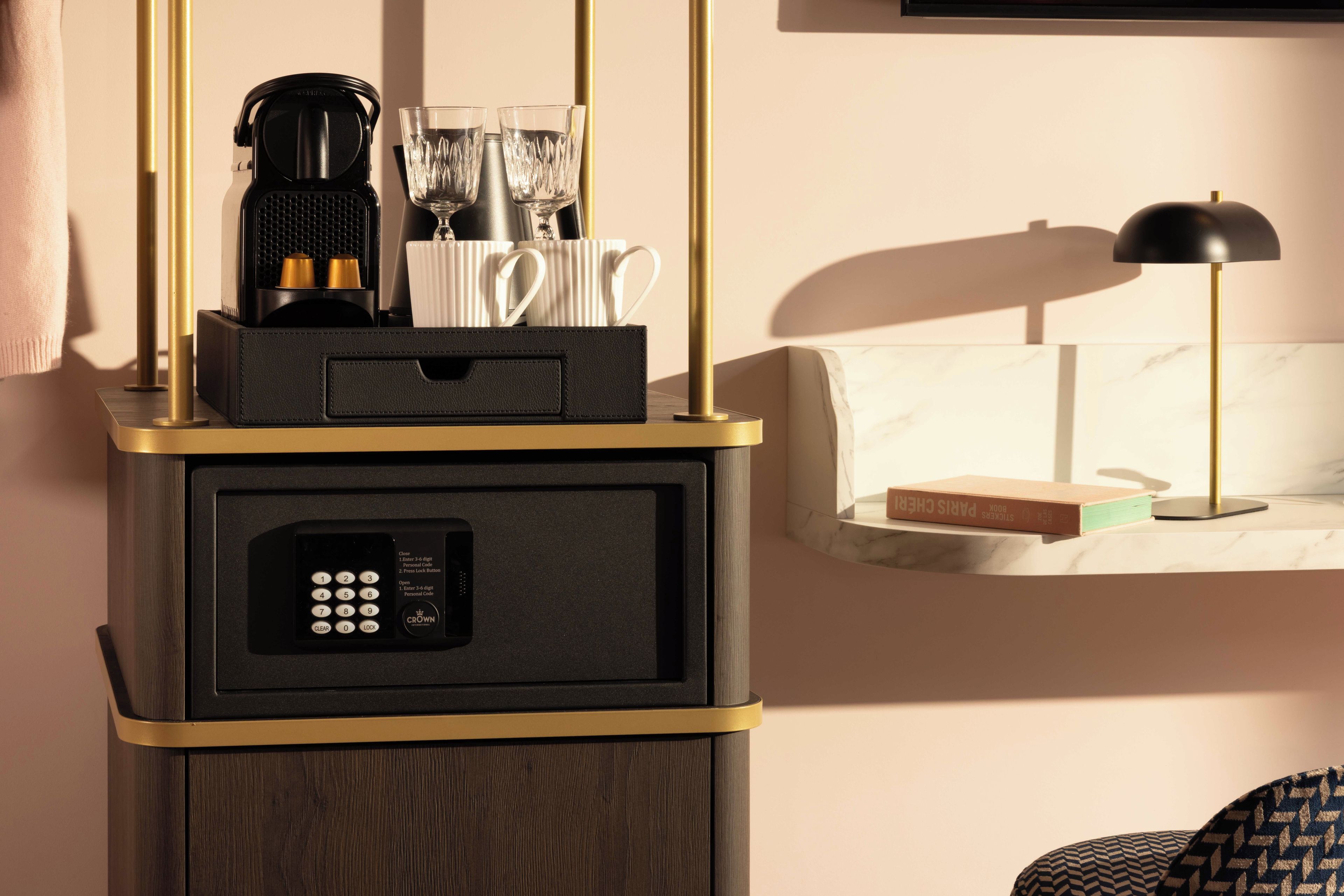 A minibar with a coffee maker, glasses, and a remote control.