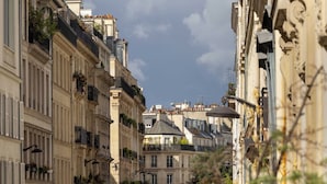 Una calle estrecha flanqueada por edificios históricos, con balcones adornados con plantas y arquitectura tradicional.
