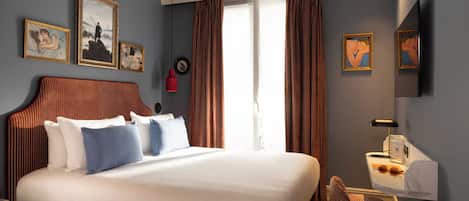 Ein Hotelzimmer mit einem großen Bett, einem Schreibtisch mit Lampe und Bildern an der Wand.