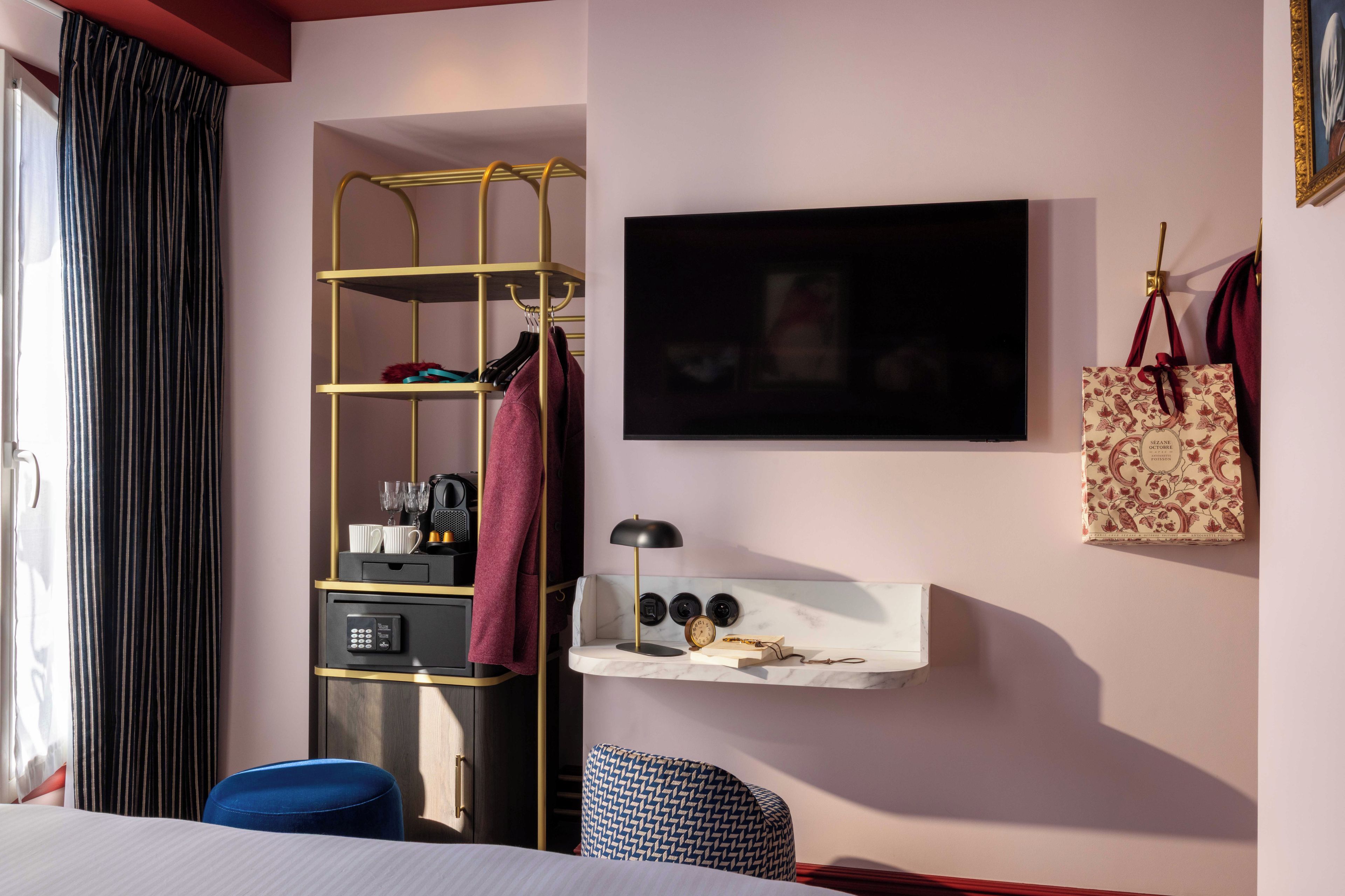 Een hotelkamer met een bed, een bureau met een koffiezetapparaat, een televisie en een plank met een tas.