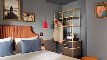 A hotel room with a bed, a wardrobe, and artwork on the walls.