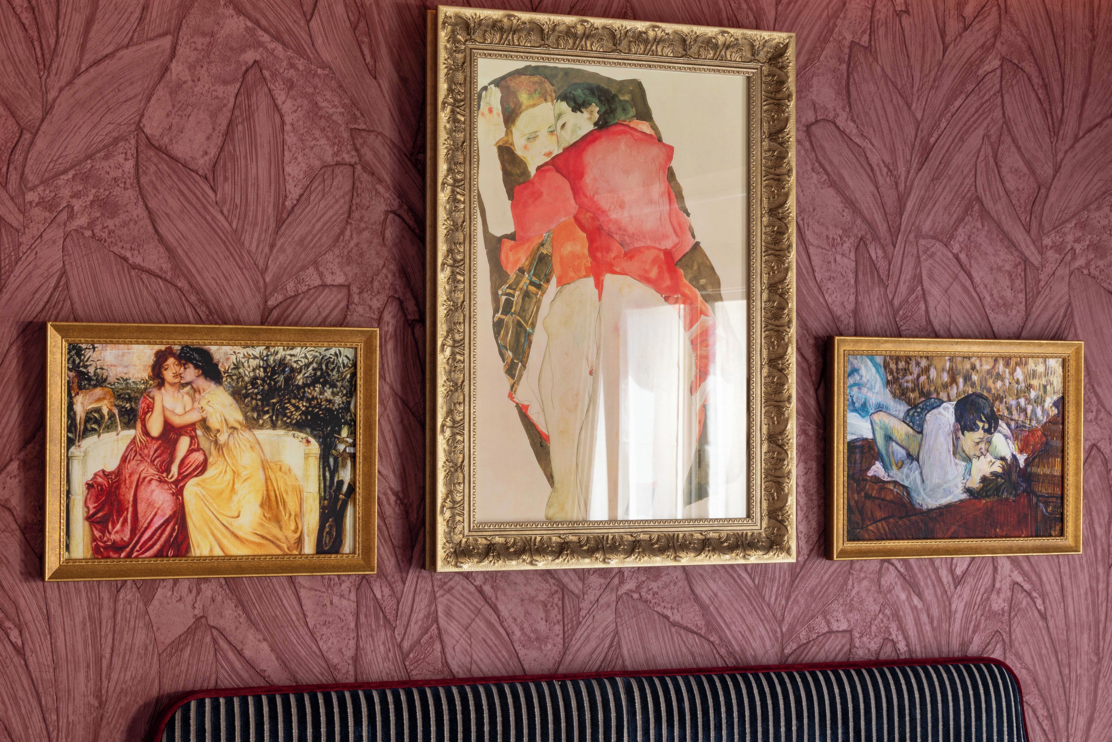 Three framed artworks on a wall with a patterned background.