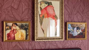 Three framed artworks on a wall with a patterned background.