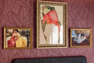 Three framed artworks on a wall with a patterned background.