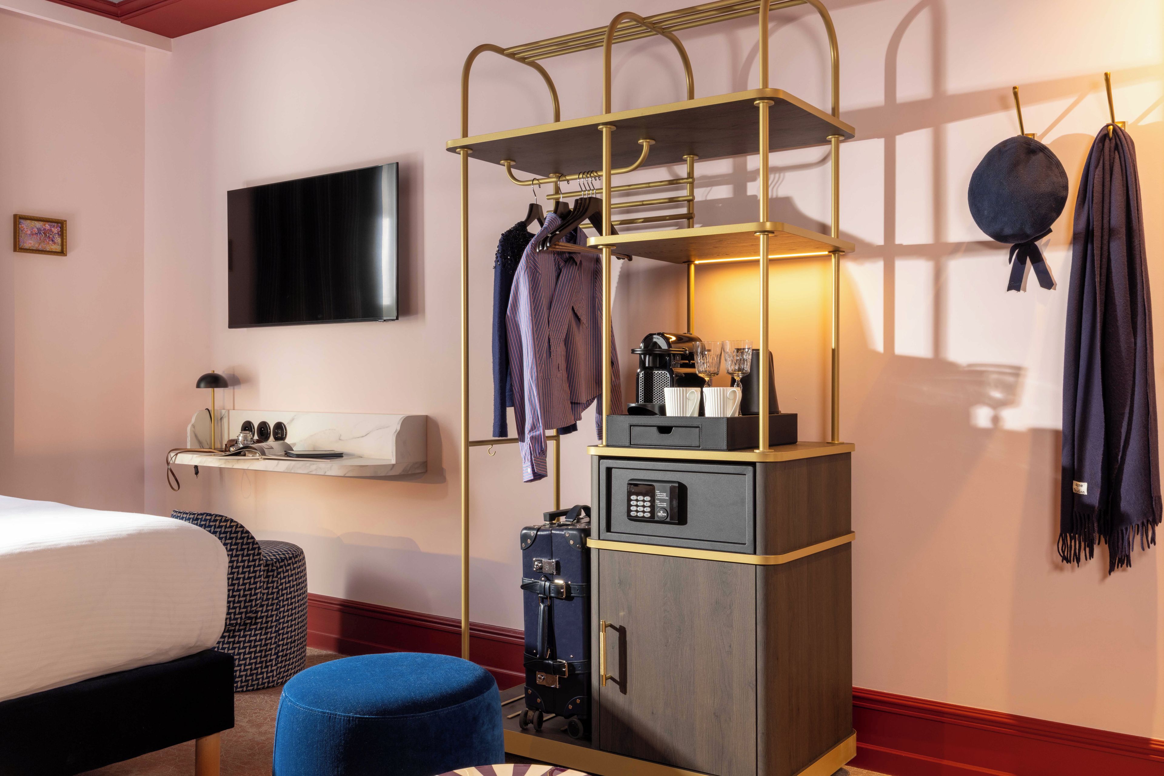 Habitación de hotel con cama, escritorio con computadora, armario y televisor en la pared.