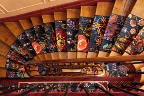 A spiral staircase with ornate floral carpet runners and a central handrail. - Grand Hotel De Turin (Paris)