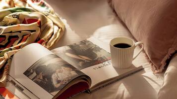 Un livre, une tasse de café et un oreiller sur un lit.