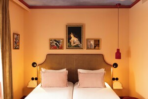 Ein Doppelbett mit zwei Kissen, ein Kopfteil mit vertikalen Linien und drei gerahmte Kunstwerke an der Wand.