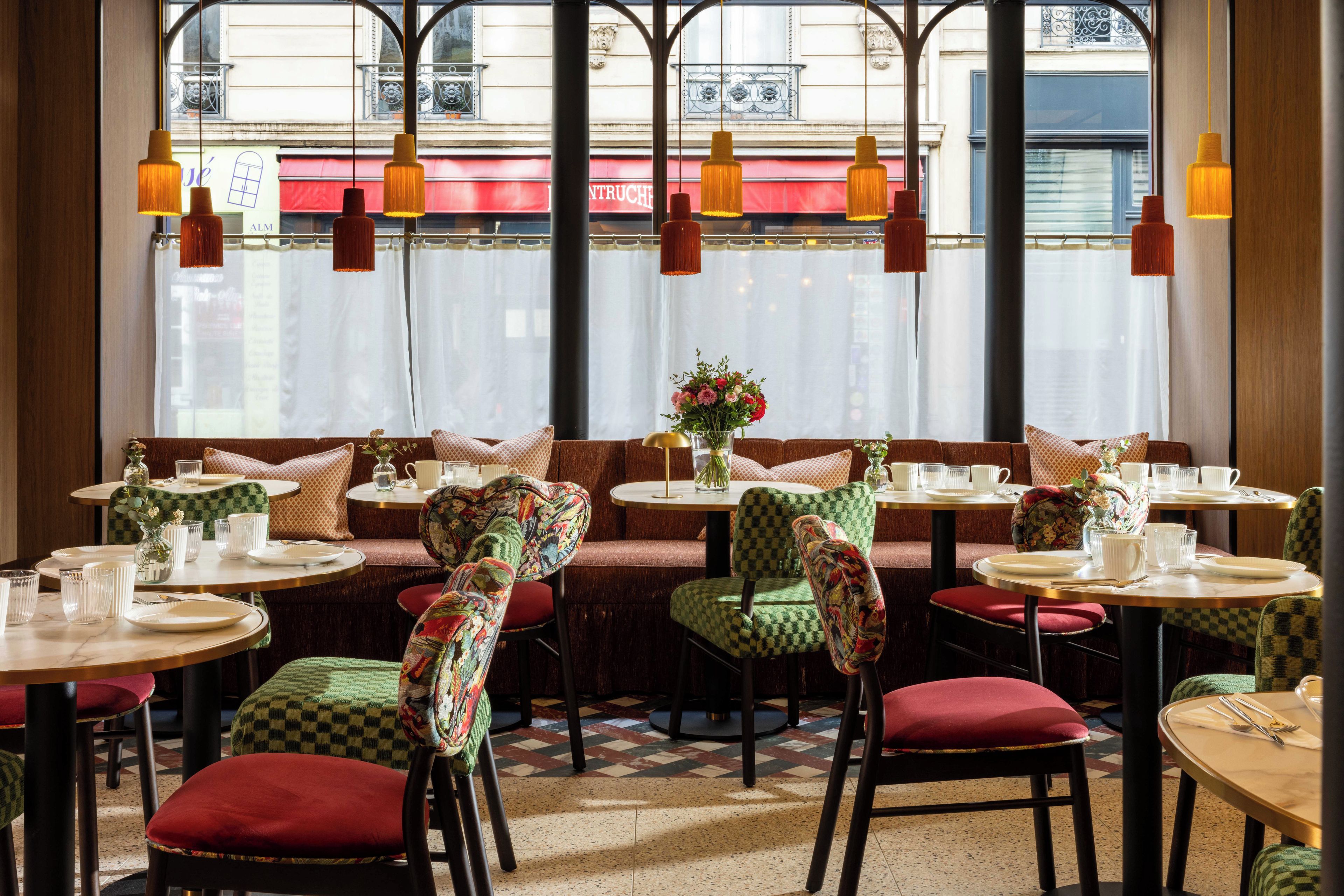 A restaurant interior with checkered chairs, round tables, and hanging pendant lights.