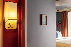 Una camera d'albergo con una targa con il numero, un quadro incorniciato e un letto con tende.