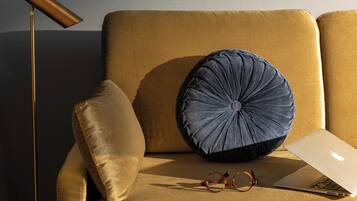 Ein Sofa mit Laptop und Brille, eine Stehlampe und ein Kissen.