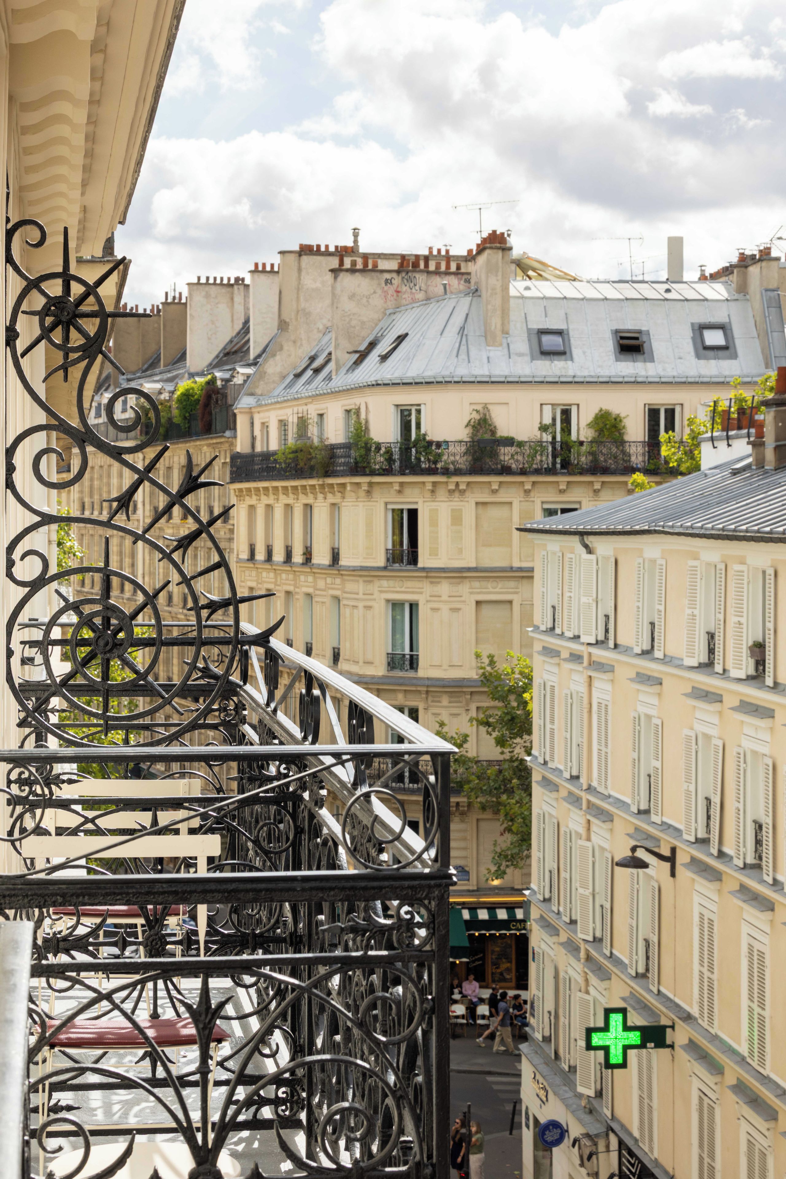 A balcony with ornate wrought iron railings overlooking a street with buildings.
