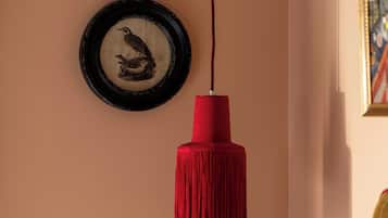 Un muro con un quadro di un uccello e un passamaneria rosso appeso al soffitto.