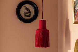Un mur orné d’un tableau encadré représentant un oiseau, et une frange rouge suspendue au plafond.