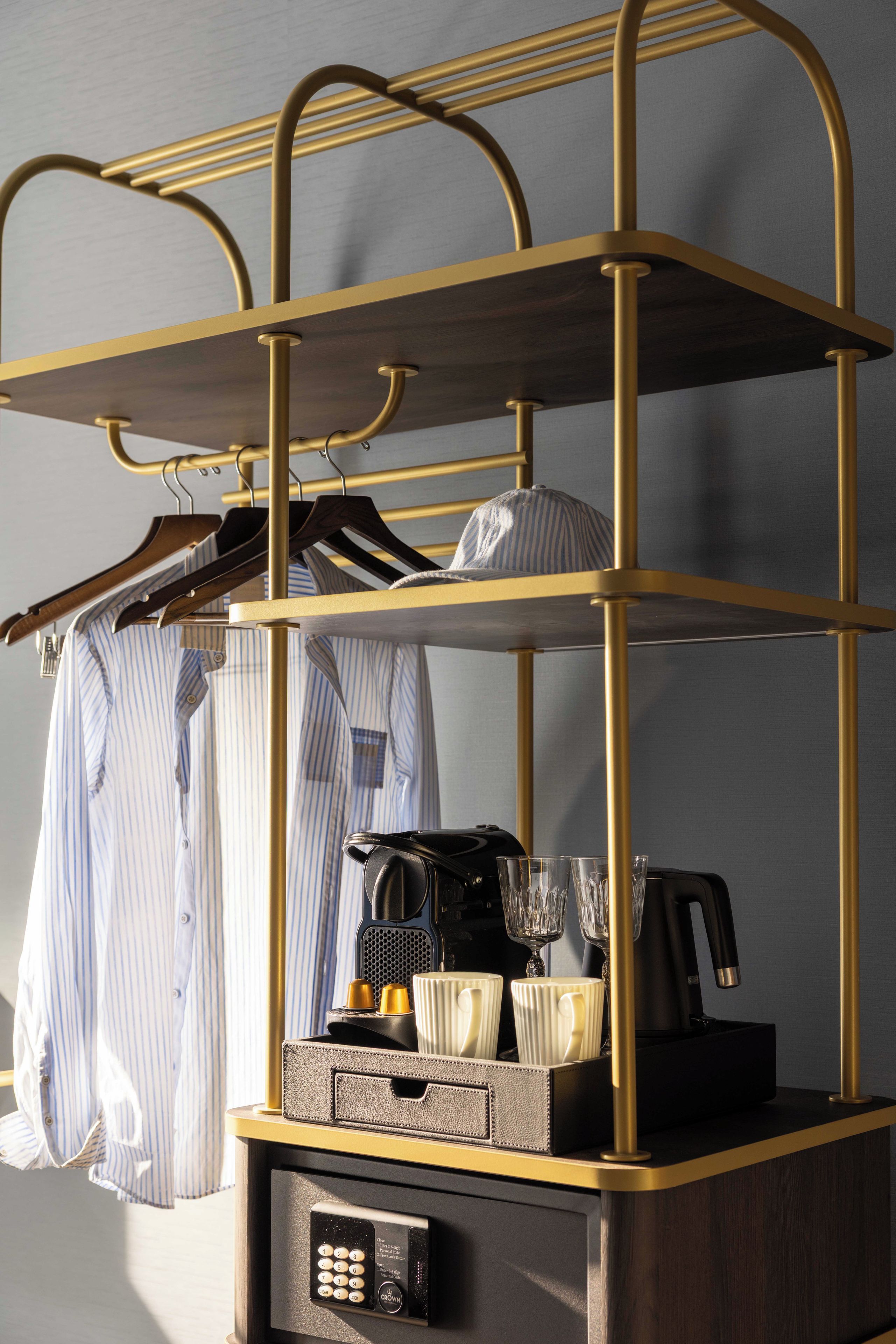 A multi-tiered metal rack with clothing and a coffee machine.