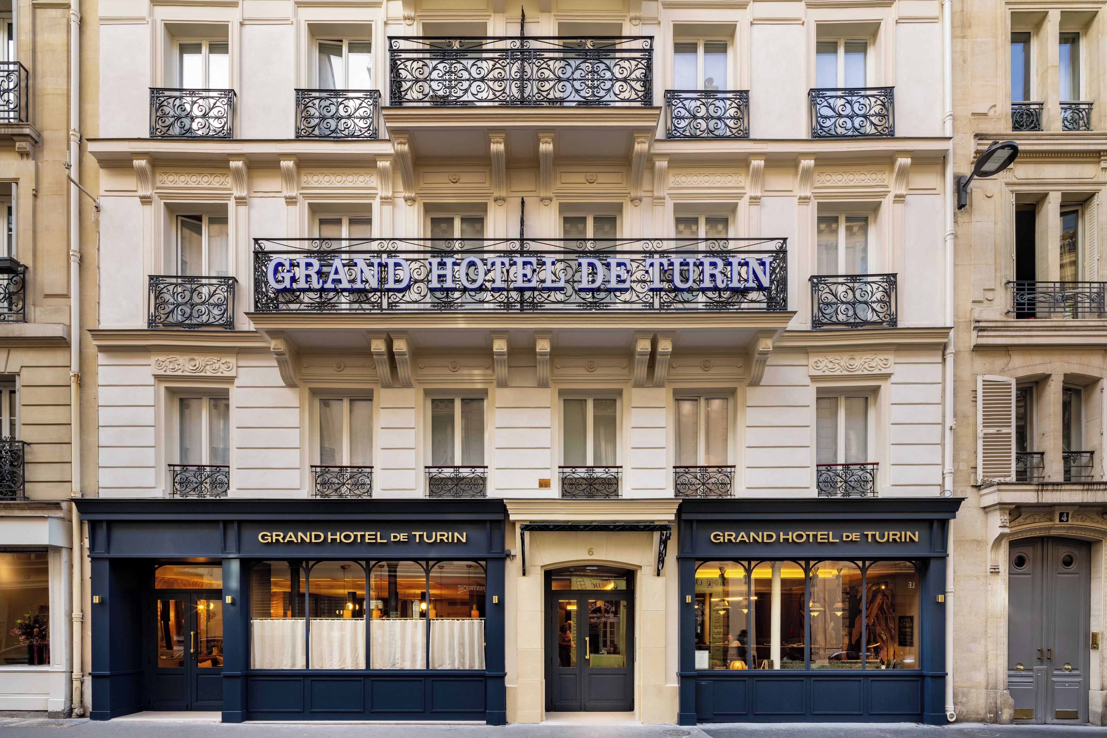 Un edificio con un letrero que dice 'GRAND HOTEL DE TURIN' sobre la entrada.