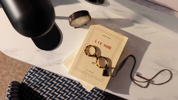 Una mesa de mármol con un libro, gafas y un reloj.