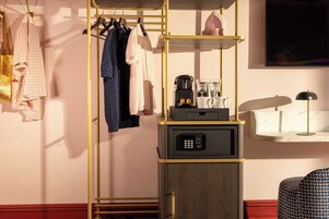 A hotel room with a wardrobe, a coffee machine, and a bedside table with a lamp.