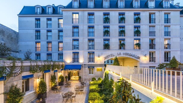 Un hôtel doté d’une cour intérieure aménagée avec des espaces de détente en plein air, un espace couvert et un escalier menant aux étages supérieurs.