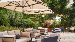 Un espace extérieur aménagé en terrasse, doté de différents types de sièges, notamment des canapés et des fauteuils, et entouré d’une végétation luxuriante.