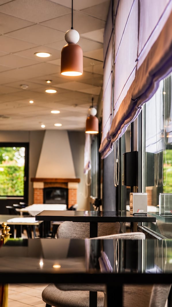 A modern interior with a long dining table, pendant lighting, and a fireplace.