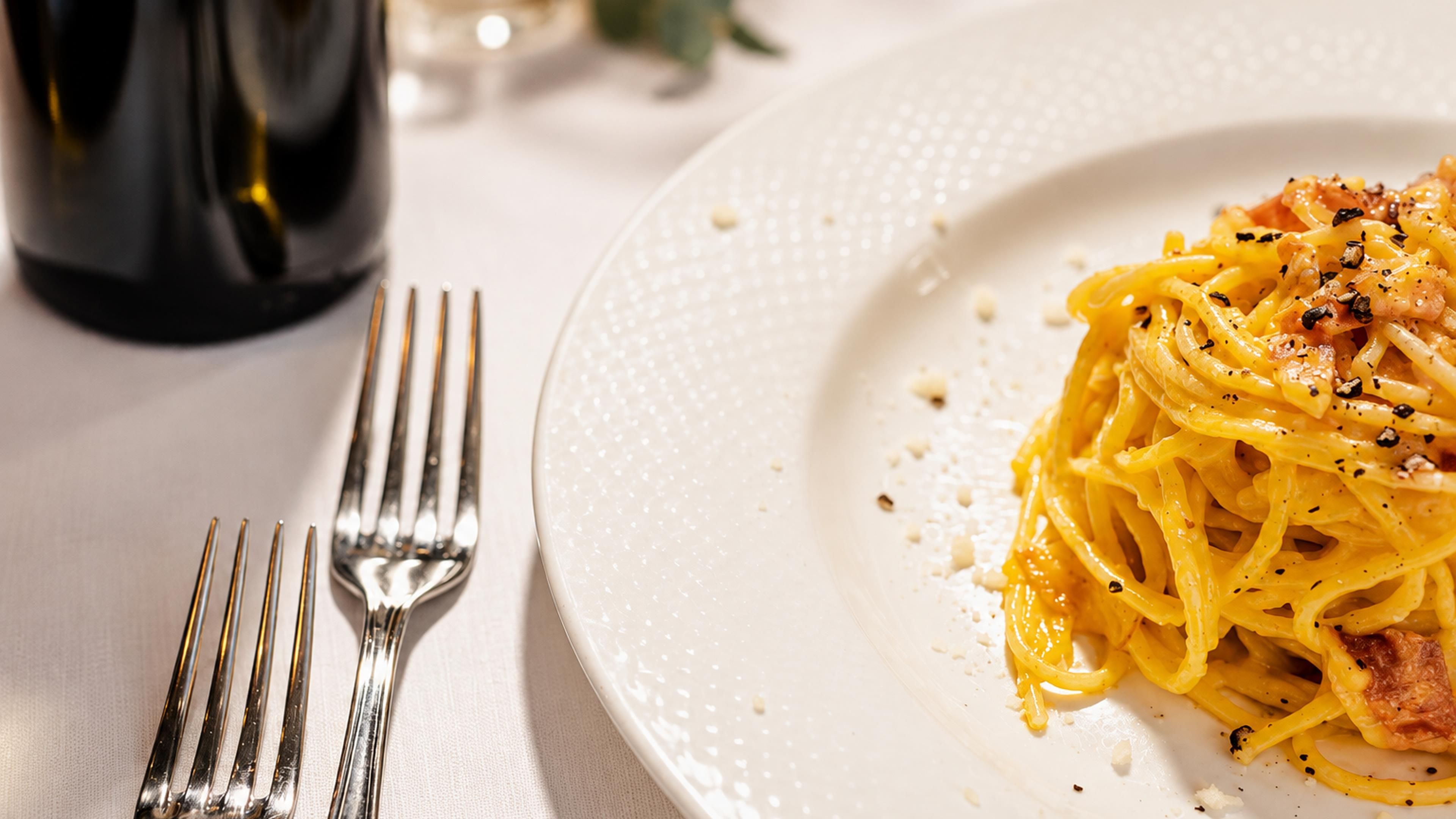 Un plato de espagueti con un tenedor a un lado sobre una mesa.