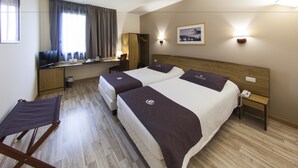 Una habitación de hotel con dos camas, un escritorio, una silla y una mesita.