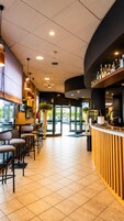 Un interior moderno con zona de bar, asientos y vistas a través de puertas de vidrio.