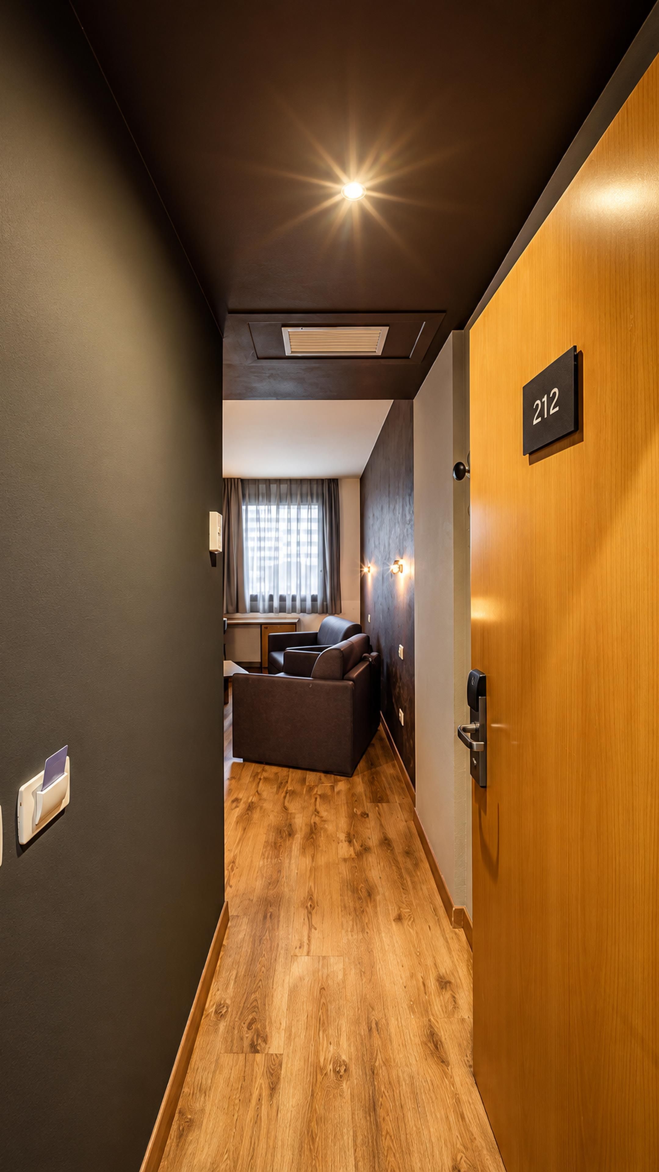 Un pasillo que conduce a una habitación con una puerta de madera con el número 212.