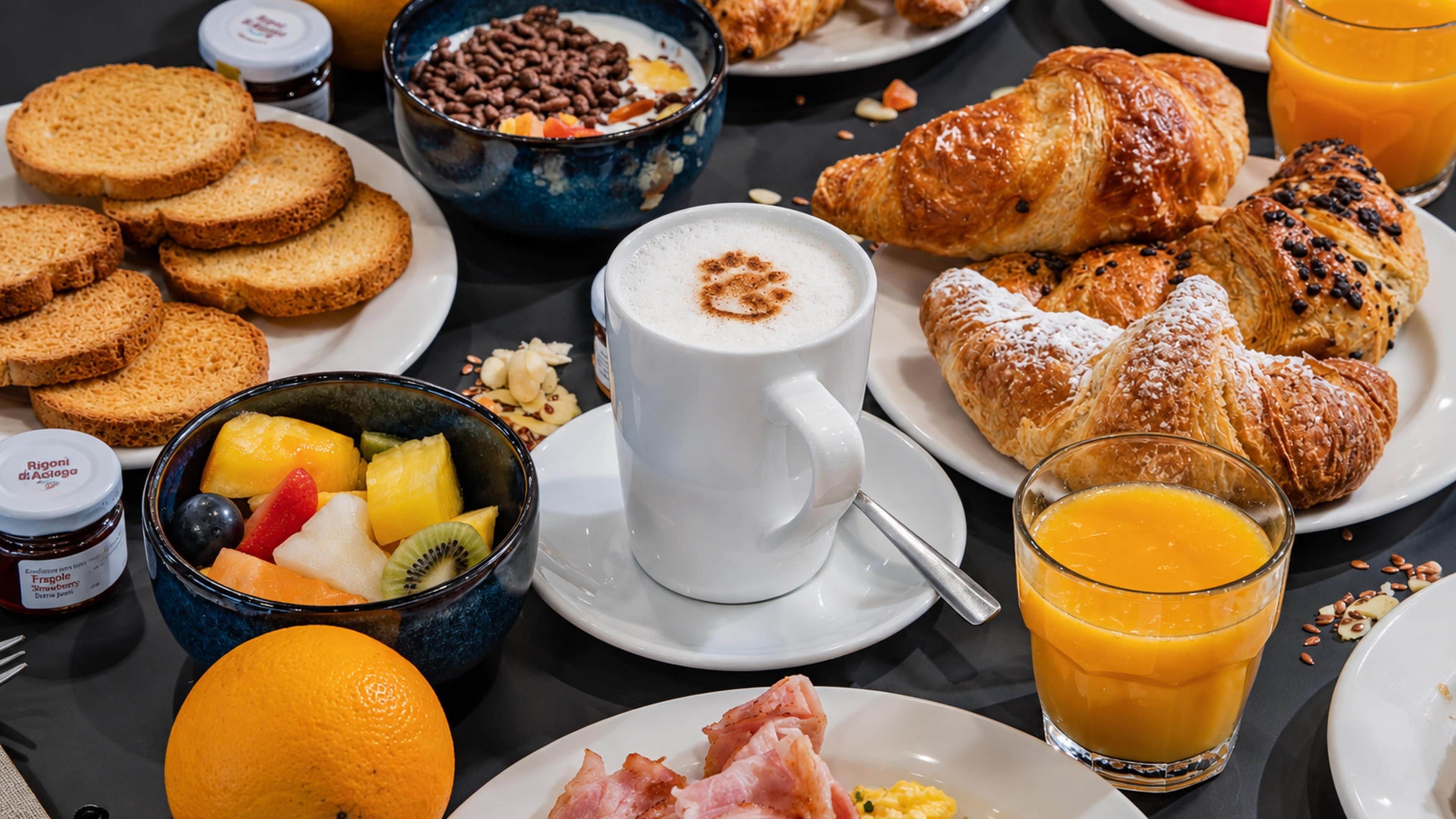 Une table de petit-déjeuner avec des croissants, des fruits, du café et du jus d’orange.