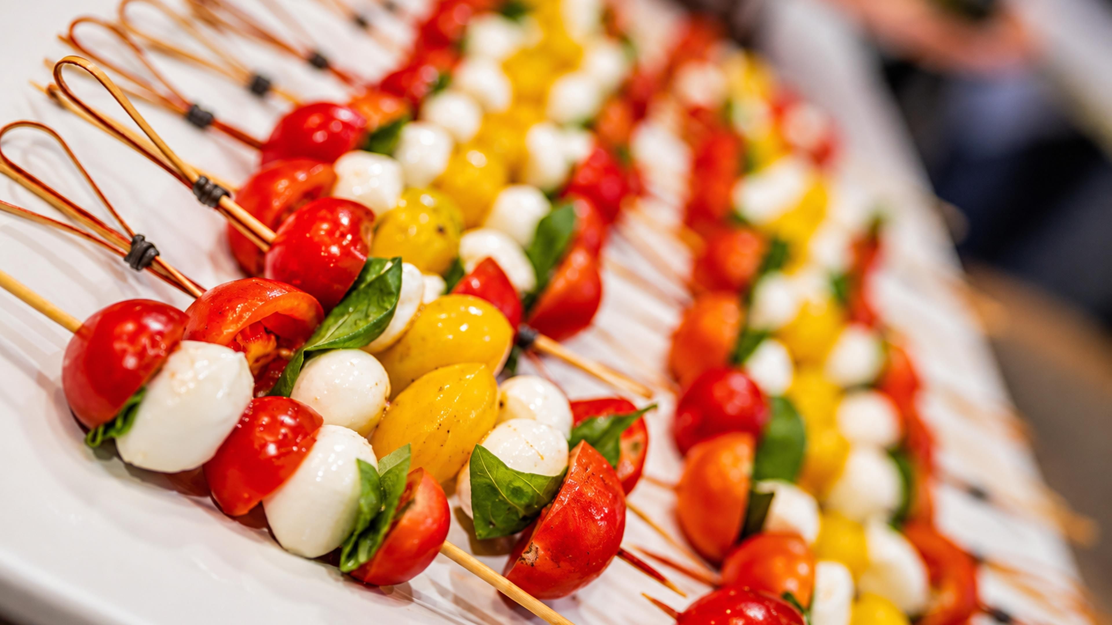 A plate of skewered vegetables and mozzarella cheese.