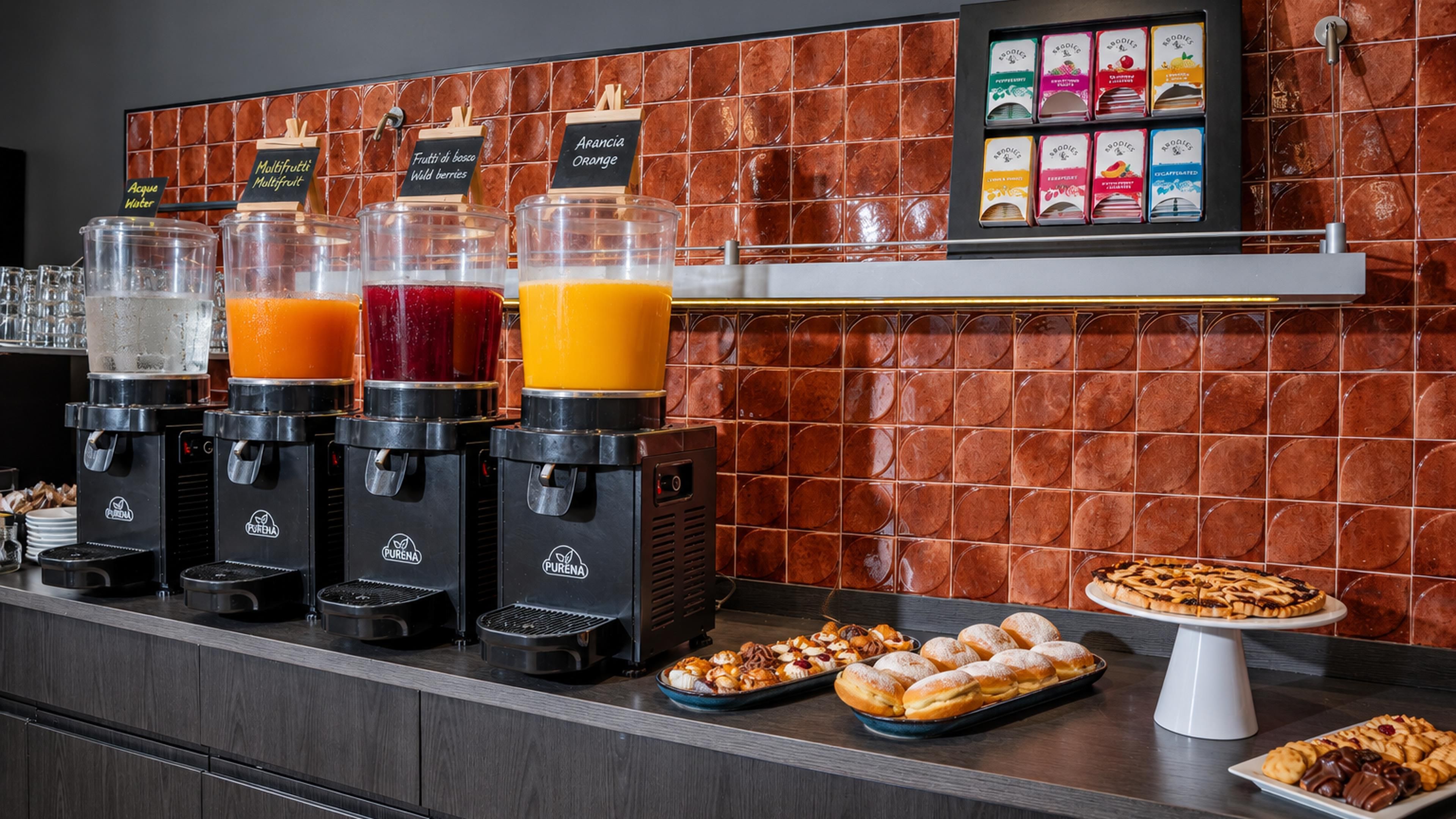 Una colazione a buffet con diversi distributori di succo, una selezione di pasticcini e uno schienale piastrellato.