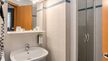 Ein Badezimmer mit Waschbecken, Spiegel, Handtuchhalter und einer Duschkabine.