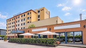 A hotel with a prominent 'Tulip Inn' sign, a brick facade, and outdoor umbrellas.
