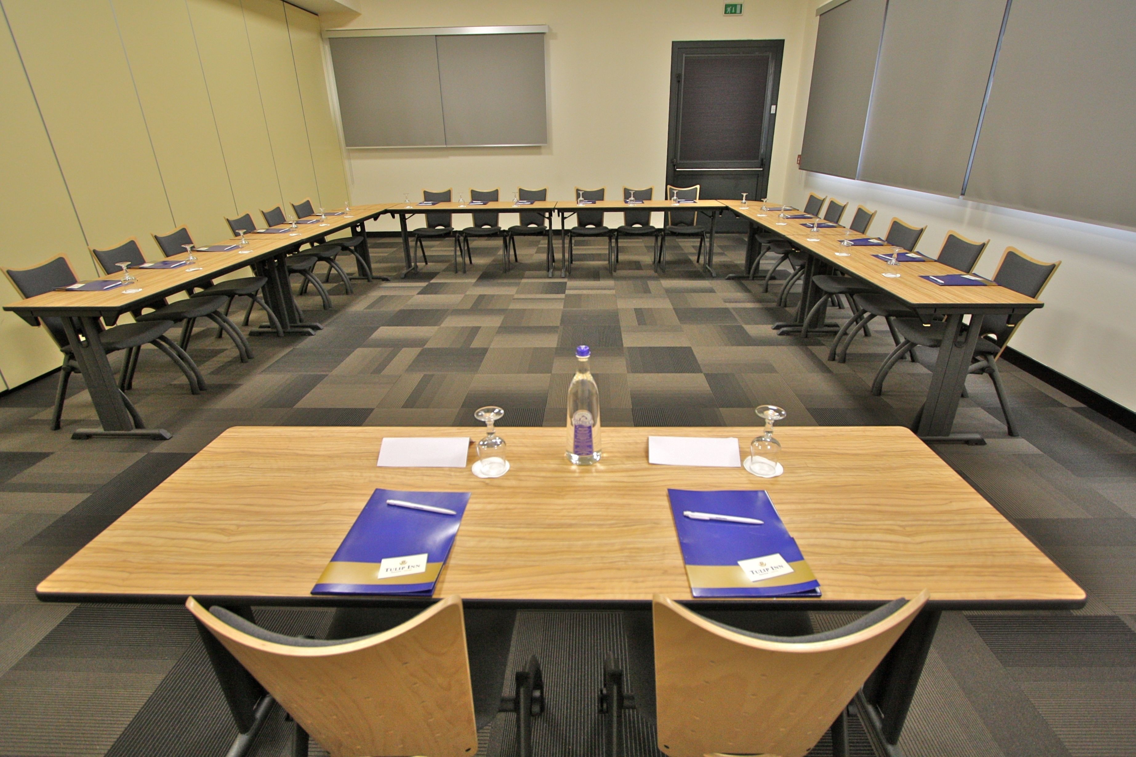 A conference room with a long table, multiple chairs, and nameplates.
