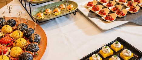 Una mesa de buffet con distintos alimentos, como camarones, hamburguesas y postres.